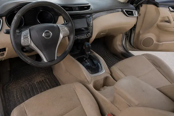 Dusty Nissan car interior before professional interior detailing in Fresno.